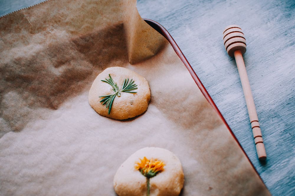 two shortbread cookies next to wooden honey spoon