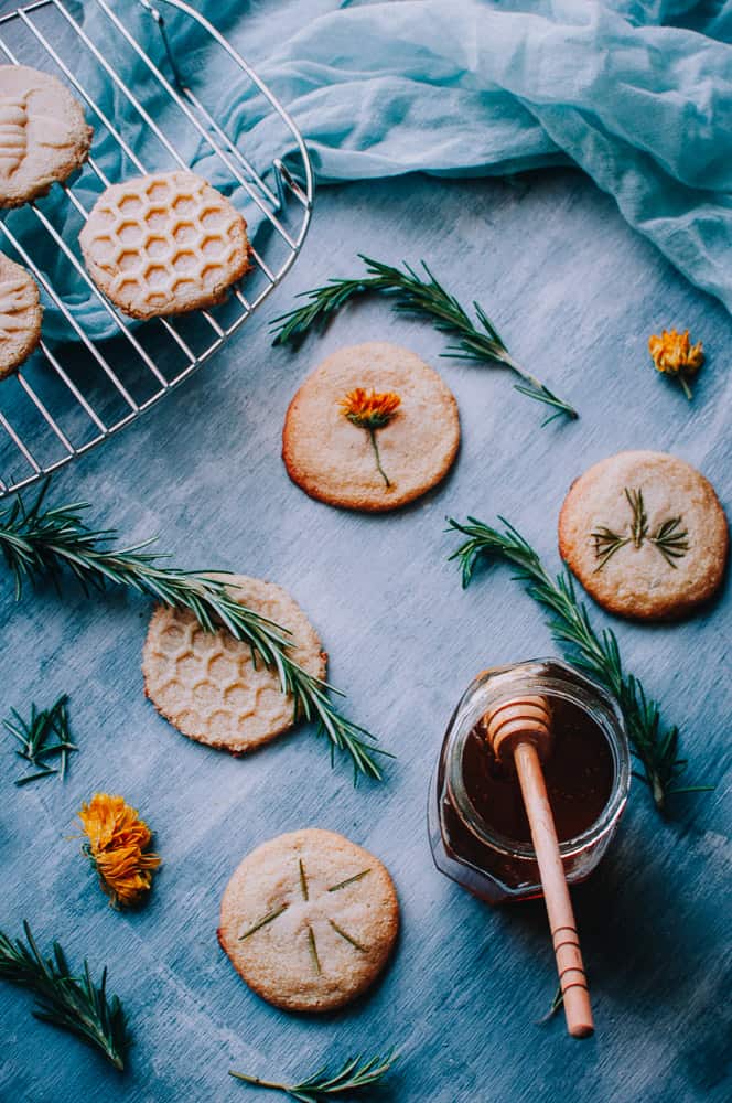 honey spoon dipped in honey next to gluten free shortbread cooling on a rack