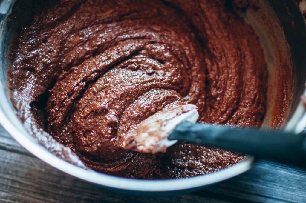 a mixing bowl filled with a shiny chocolate batter