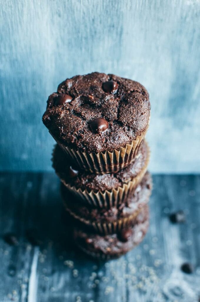 a close up shot of a stack of chocolate zucchini muffins dotted with chocolate chips