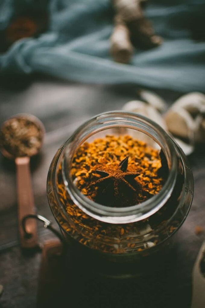 a star anise pod rest on a jar of turmeric root