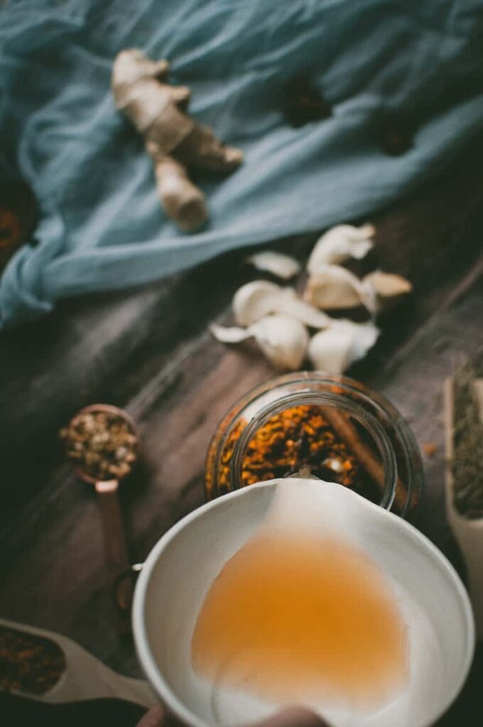 a hand pouring apple cider vinegar into a jar