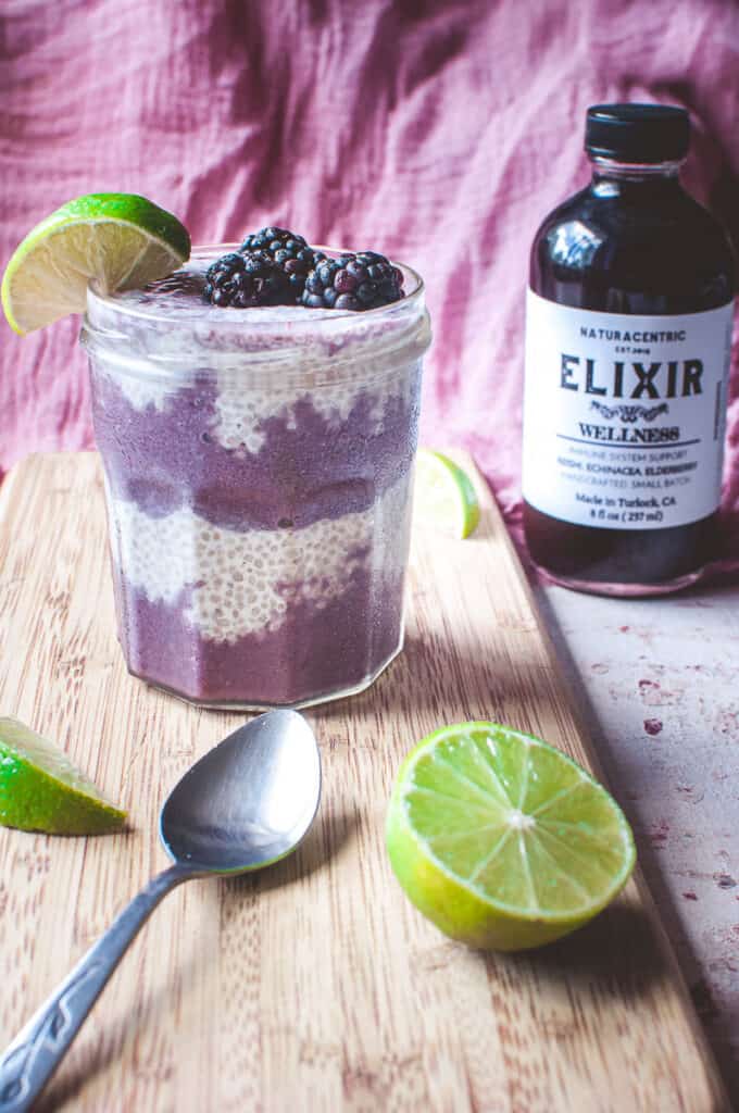 a frosty glass of chia seed parfait alongside a bottle of naturacentric wellness elixir