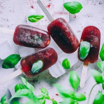 several wellness elixir ice pops stacked with a basil plant in frame