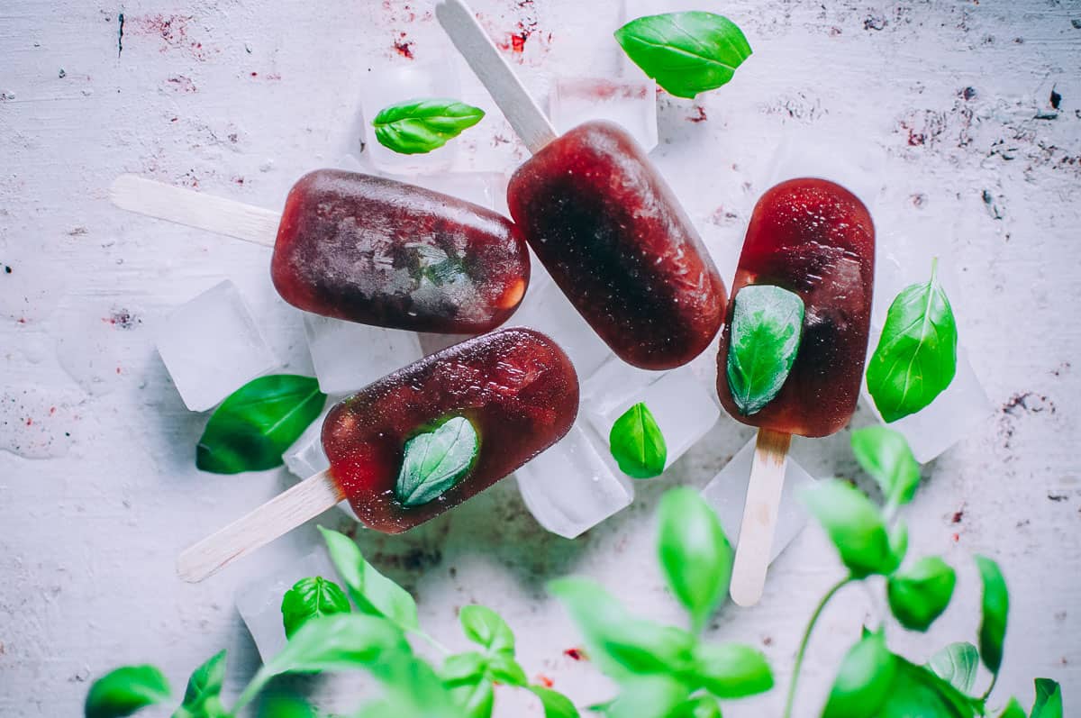 several wellness elixir ice pops stacked with a basil plant in frame