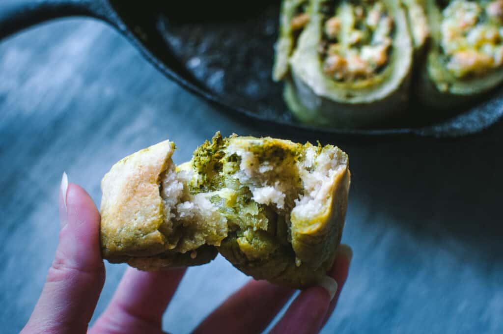 a hand holding a split open pesto roll