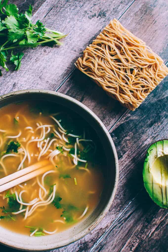 close up of ramen noodle cake next to bowl of pho