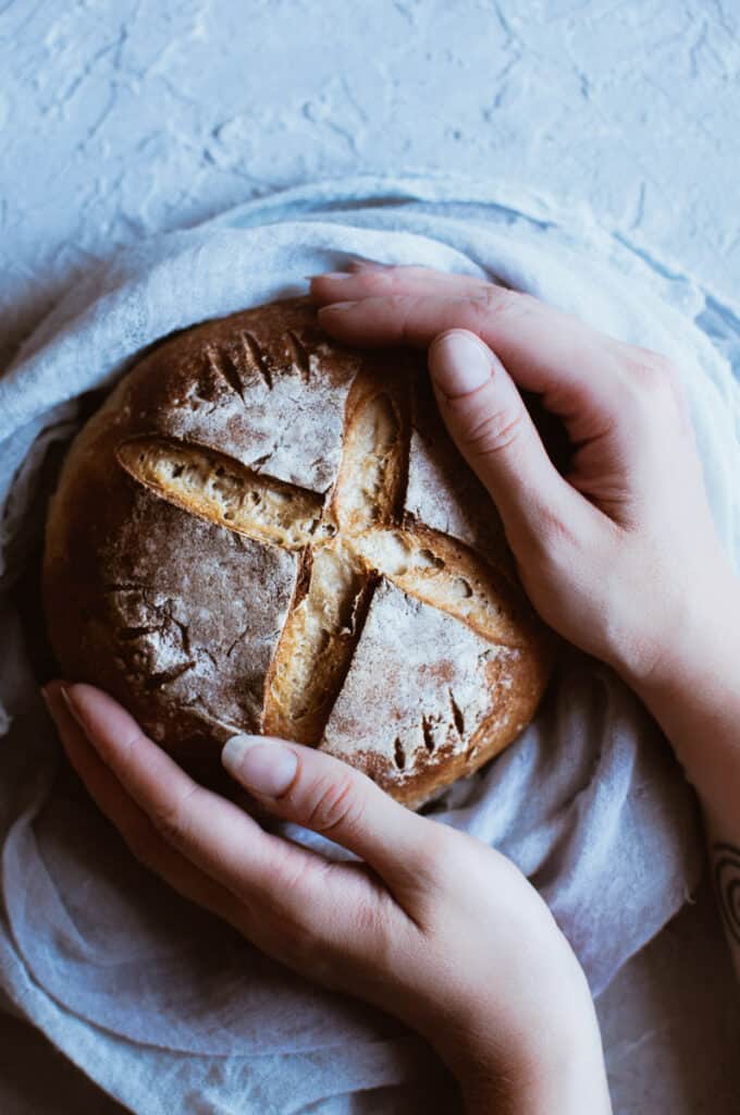 hands holding a rustic bread boule