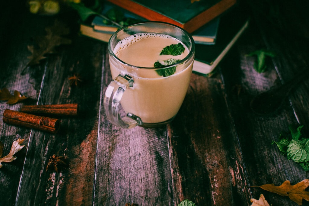 a clear mug filled with peppermint chai on a wooden background