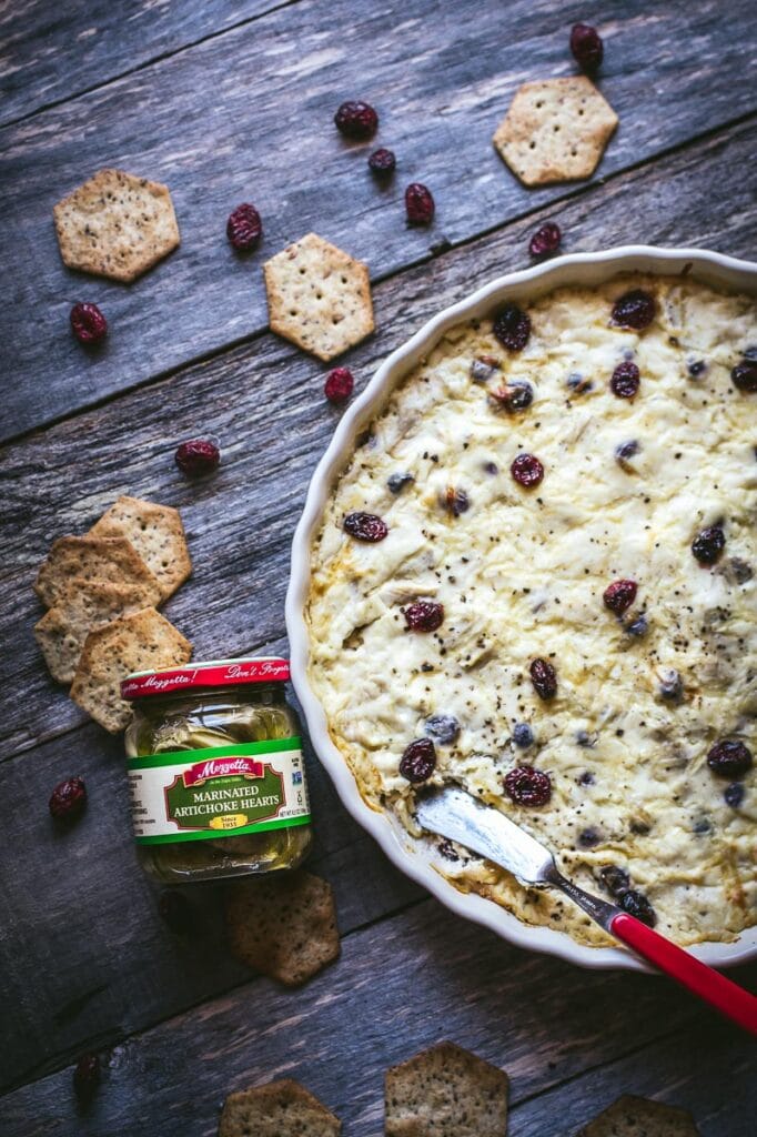 a white dish filled with cranberry artichoke dip