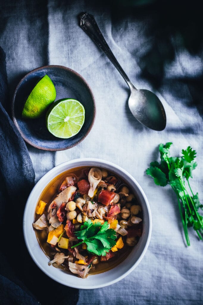 a top view of a bowl of instant pot jackfruit chili next to lime and cilantro