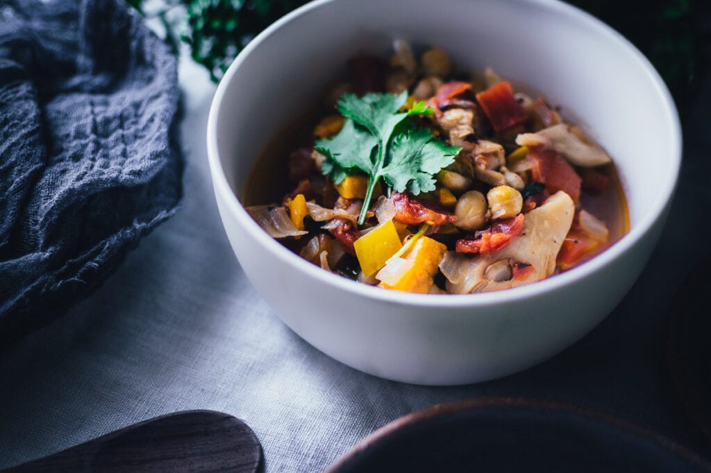 a white bowl filled with jackfruit chili topped with fresh green cilantro