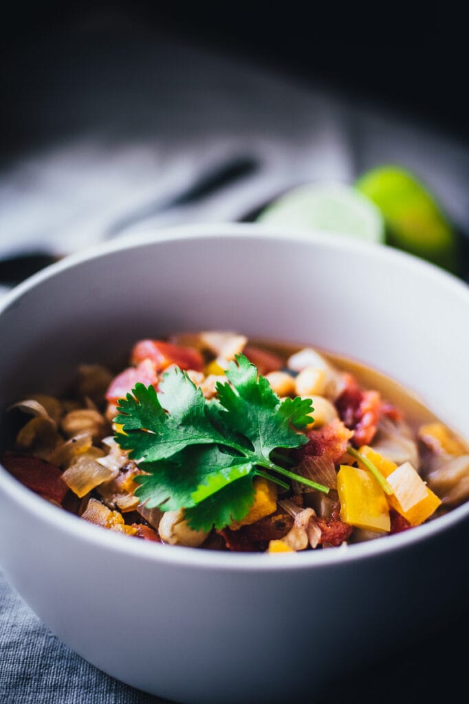 a close up shot of cilantro on top of a white bowl of chili