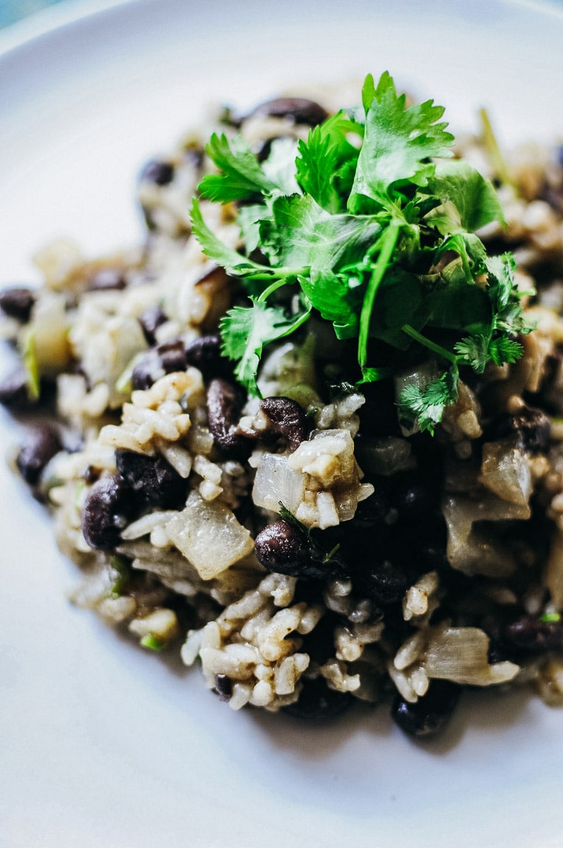 A close up shot of gallo pinto topped with cilantro on a white plate.