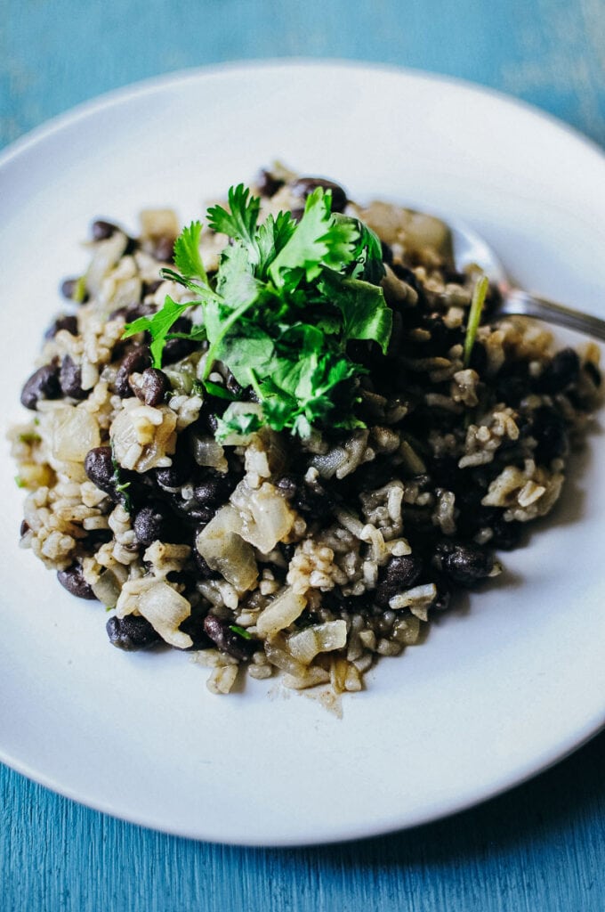 a a spoon grabbing a spoonful of gallo pinto topped with fresh cilantro leaves
