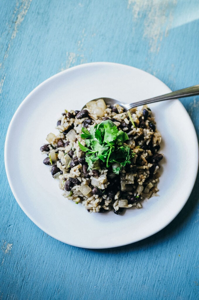 a white plate topped with costa rican gallo pinto beans and rice dish on a wooden aqua background