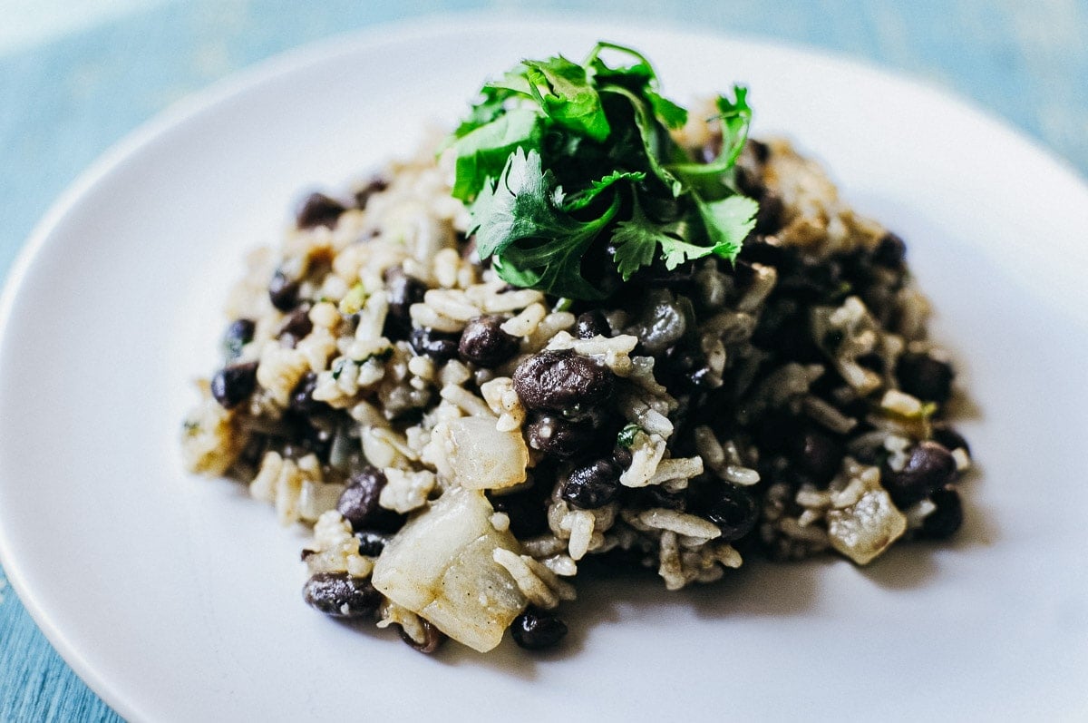 A white plate with a mound of black beans and white rice.