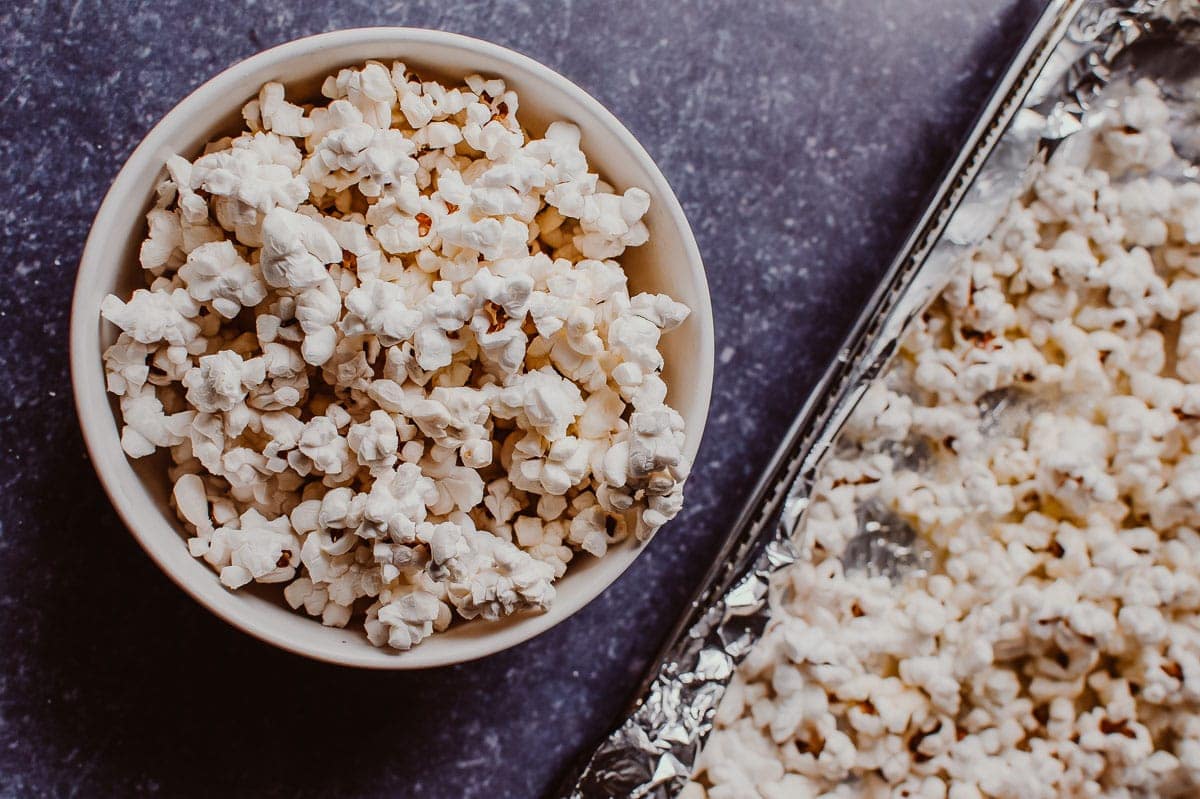 A top view of a white bowl filled with fluffy popped popcorn.