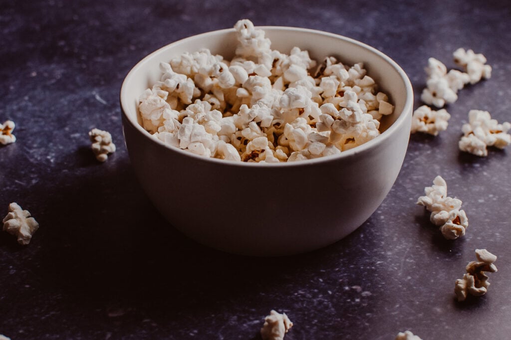 a side shot of a white bowl filled with white popcorn