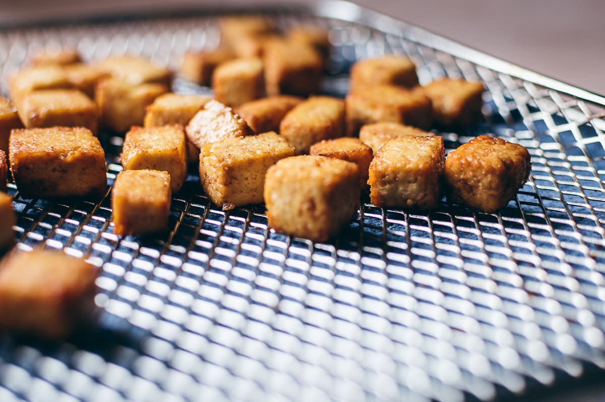 An silver rack with nuggets of cooked tofu scattered about.