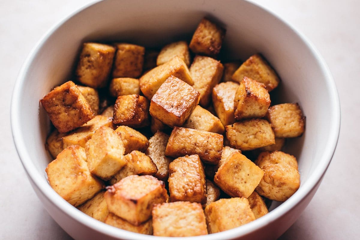 A white bowl of crispy looking tofu.