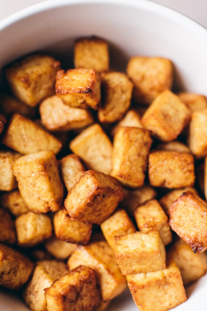 Crispy looking tofu in a white bowl.