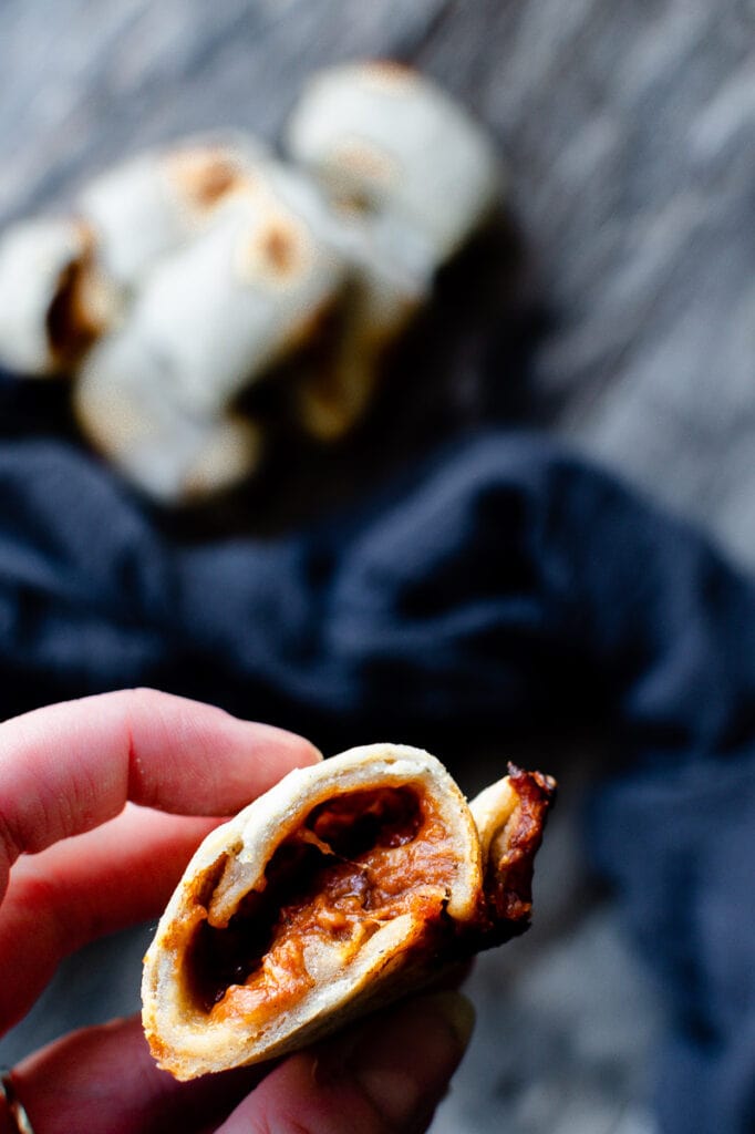 A hand holding an open pizza roll.