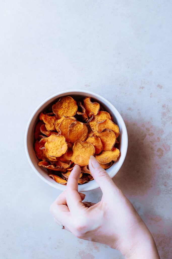 a hand reaching out to grab a sweet potato chip
