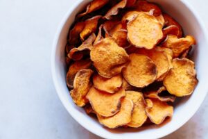 a white bowl filled with vibrant sweet potato chips