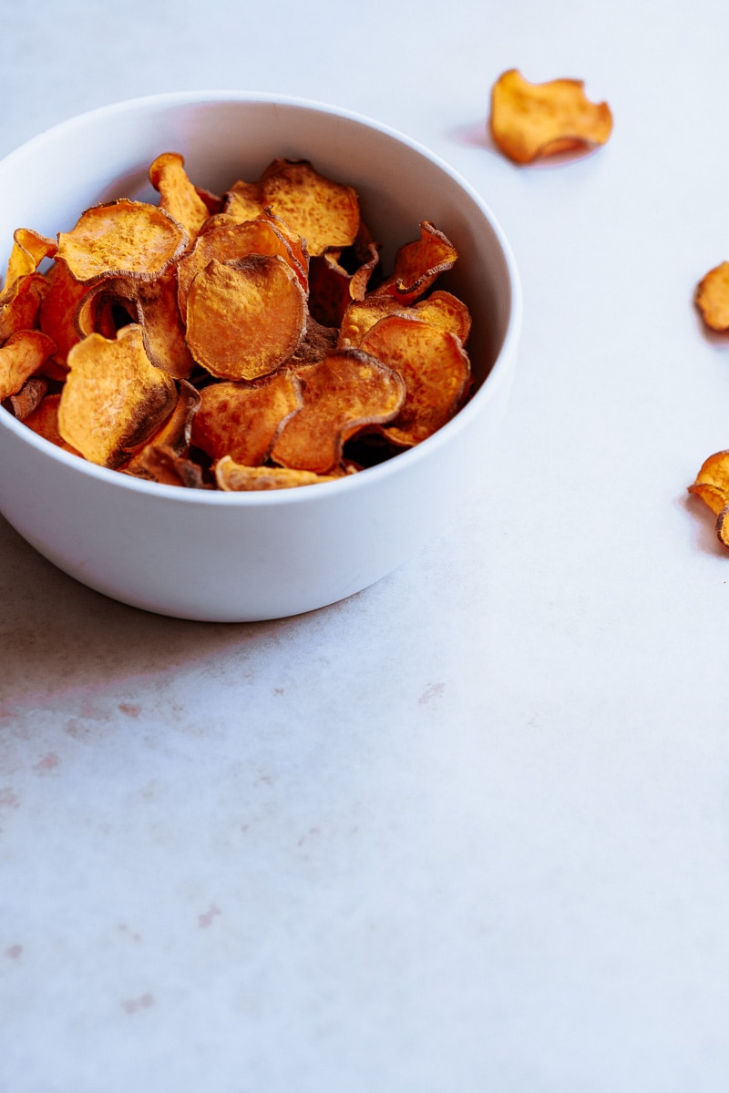 A bowl filled with crispy sweet potato chips.