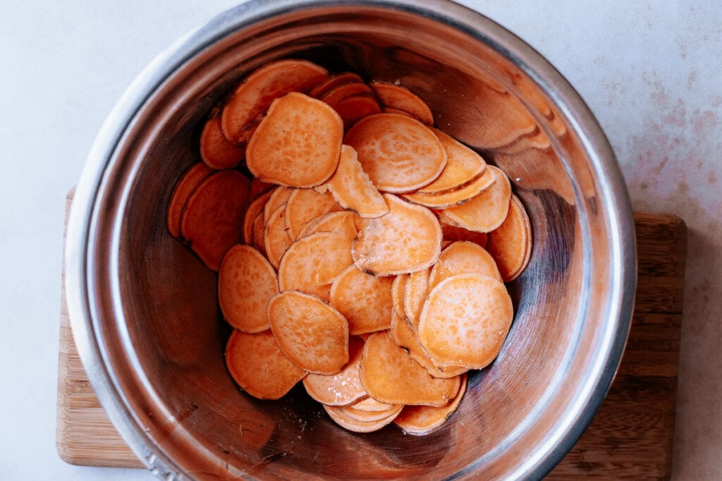 A silver bowl filled with orange sweet potato rounds.