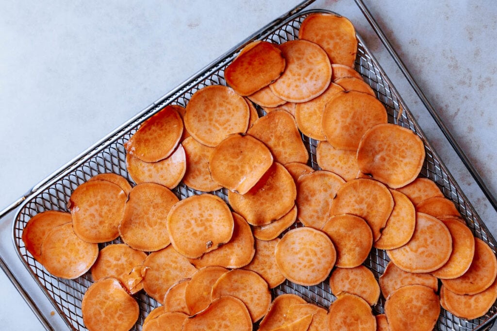 Sliced sweet potato rounds on a silver rack.