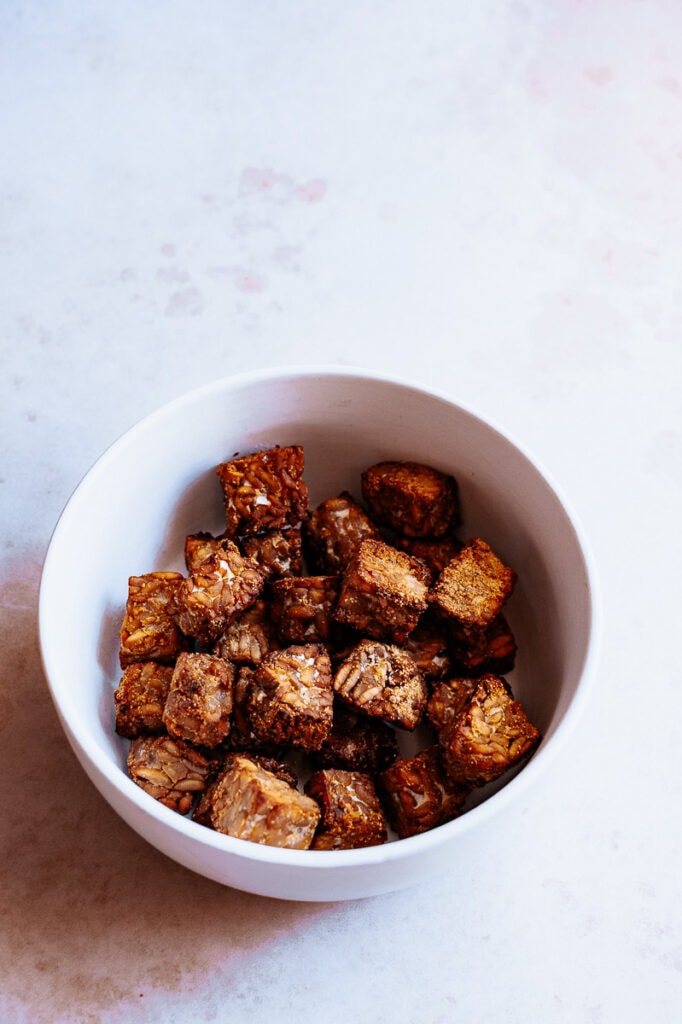 a white bowl of tempeh on a marbled background