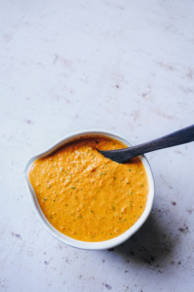 a wooden spoon stuck in a bowl of spanish romesco