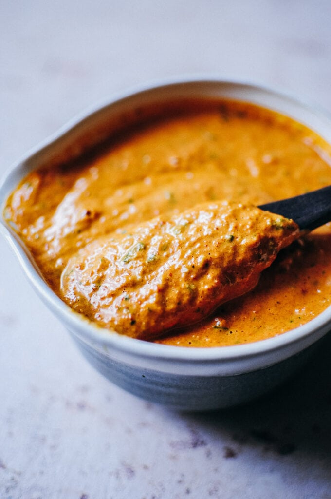 thick and creamy romesco sauce on wooden spoon lit by light