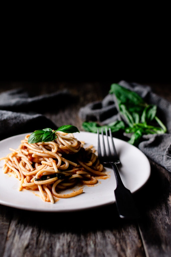 a side shot of a mount of creamy vegan pasta topped with basil leaves