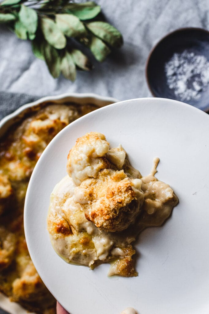 A close shot of gluten-free cauliflower cheese on a white plate.