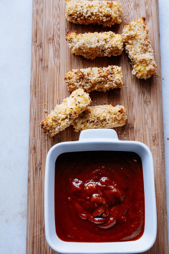 air fryer mozzarella sticks lined up on a wooden cutting board