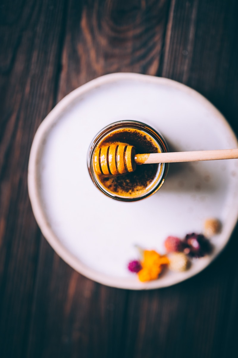 Atop shot of a honey dipper coated in extra golden shiny liquid.