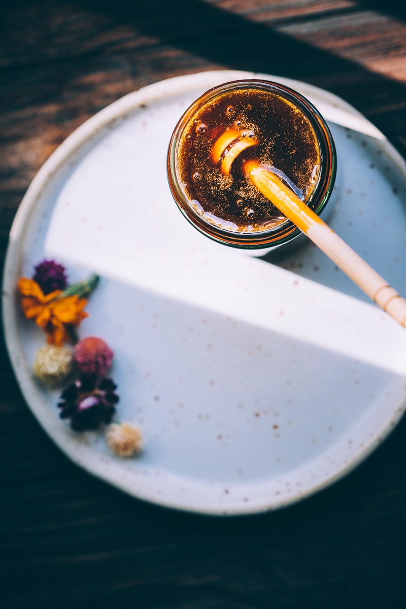 Aunlight hitting an open jar of vegan honey giving a rich golden hue.