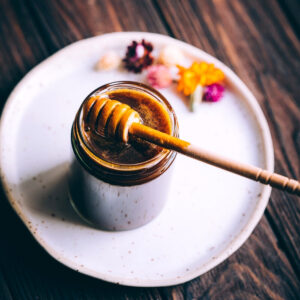 vegan honey in a jar sitting on a white plate