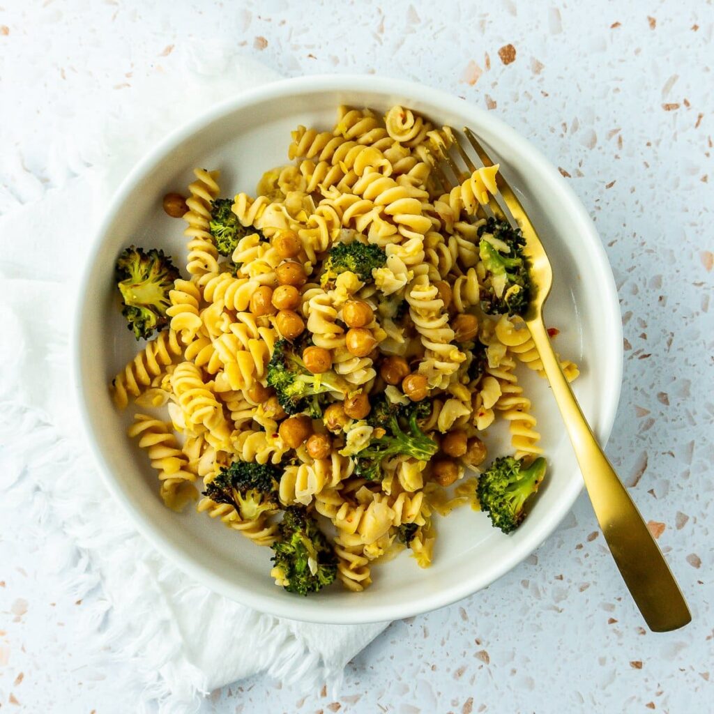 Lemon chickpea gluten-free vegan pasta in a dark bowl garnished with fresh herbs and lemon zest