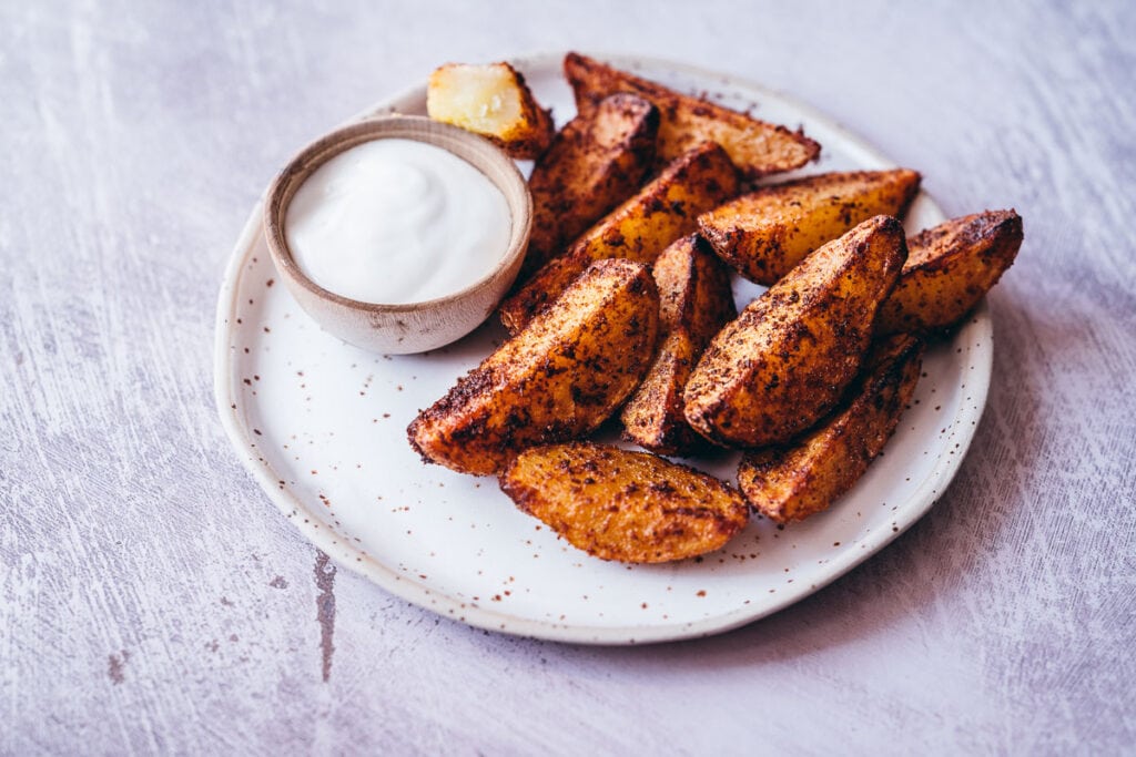 a speckled matte ceramic plate topped with crispy seasoned potato wedges