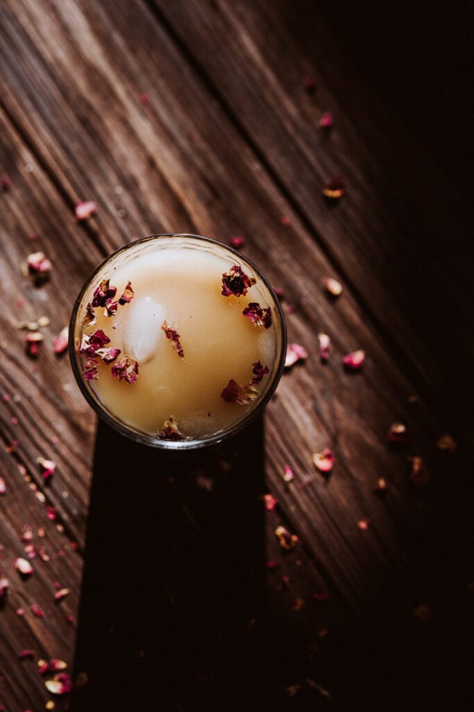 long shadows cast by a clear glass of iced rose rooibos latte