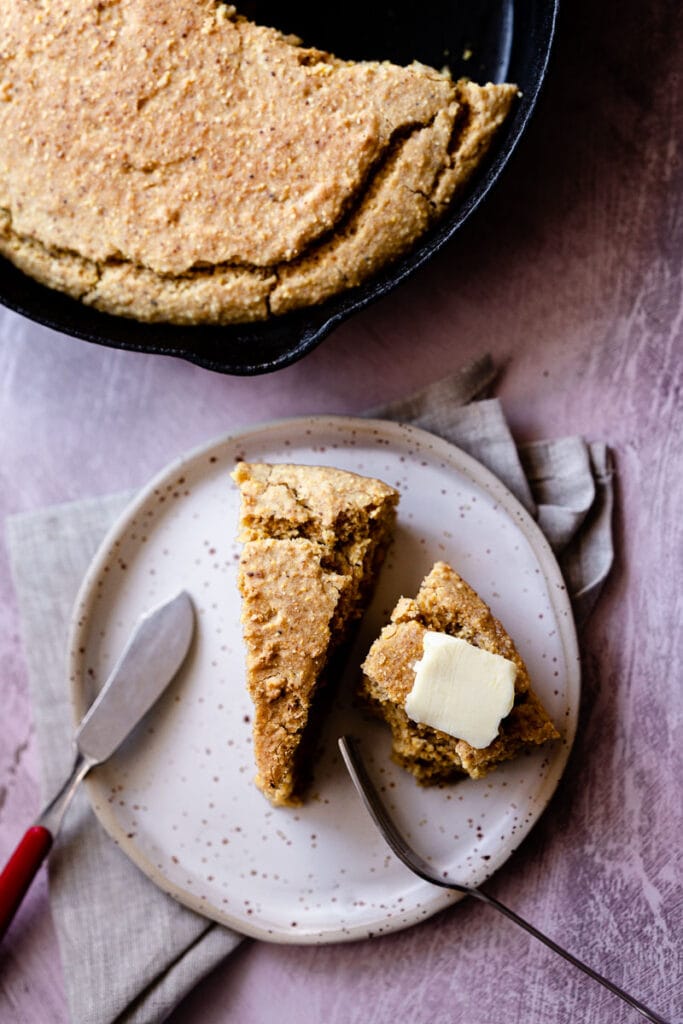 no eggs to be found in these slices of buttered gluten free cornbread resting on a white ceramic plate