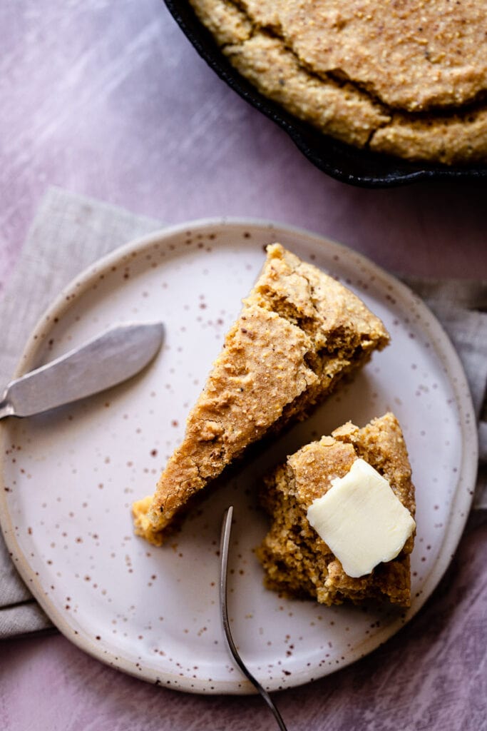 slices of vegan gluten free cornbread rest on a speckled ceramic plate from laima ceramics