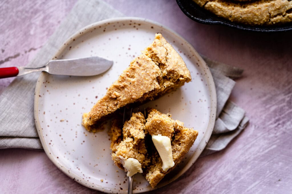 a speckled ceramic plate topped with buttered gluten-free cornbread