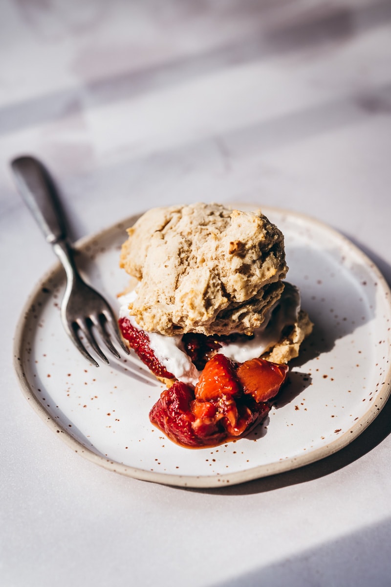 Whipped cream and strawberries sandwiched between golden shortcakes lit by the sun.