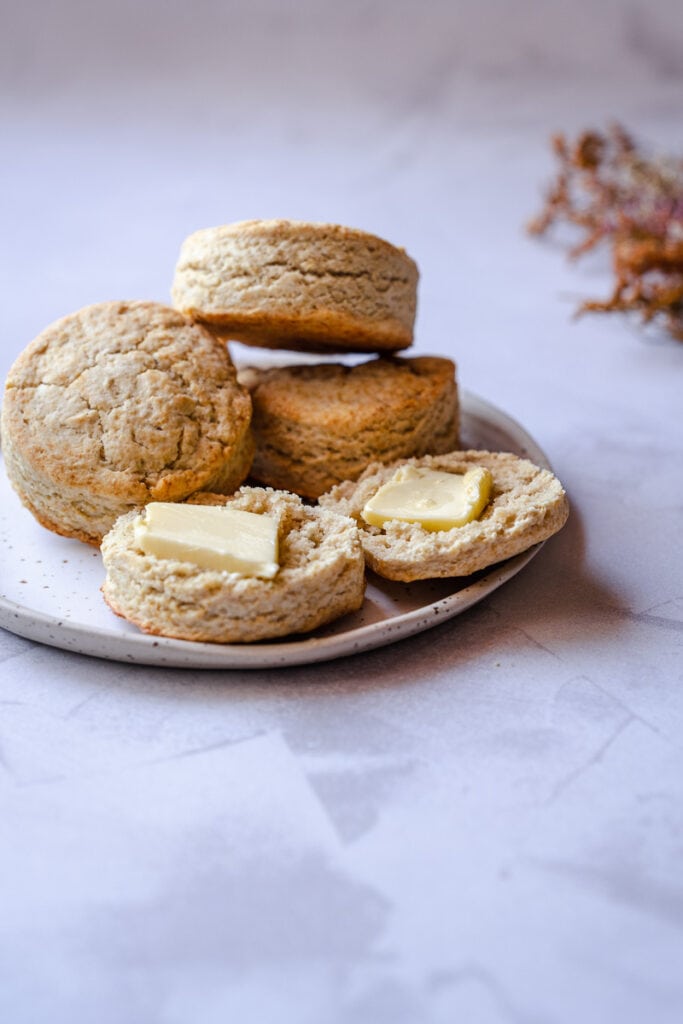a gluten free biscuit cut open and topped with pats of butter