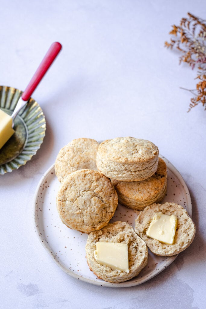 a speckled plate topped with golden gluten free biscuits served with pats of butter